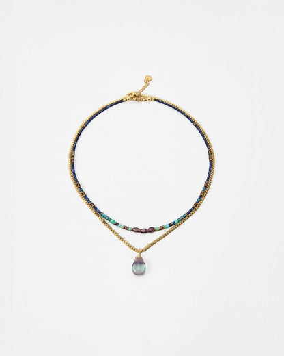 Elsita Jewelry Nomad layered necklace with blue beads, gold chain, and a teardrop gemstone pendant.