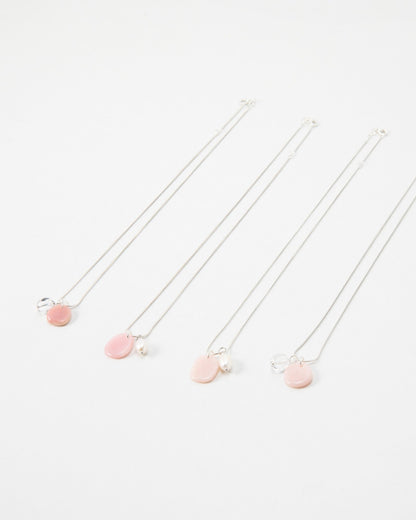 Four Elsita Jewelry Petal Clear necklaces featuring delicate silver chains with pink petal charms and pearl accents.