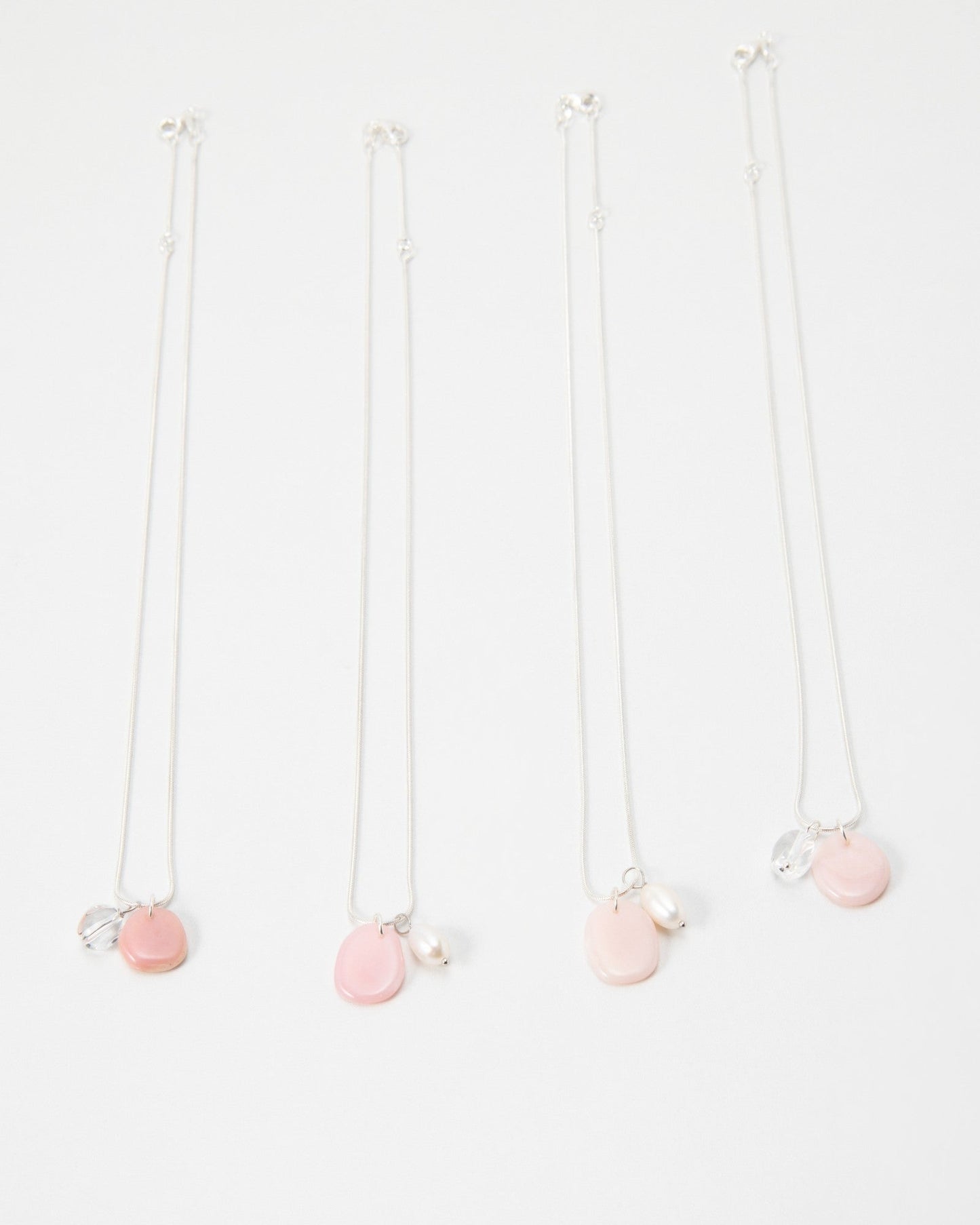 Elsita Jewelry Petal Clear necklaces featuring delicate silver chains with pink petal charms and pearl accents.