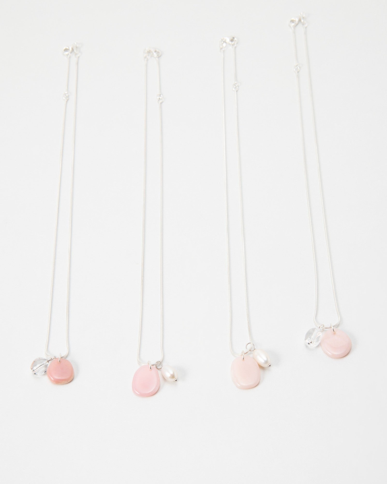 Elsita Jewelry Petal Clear necklaces featuring delicate silver chains with pink petal charms and pearl accents.