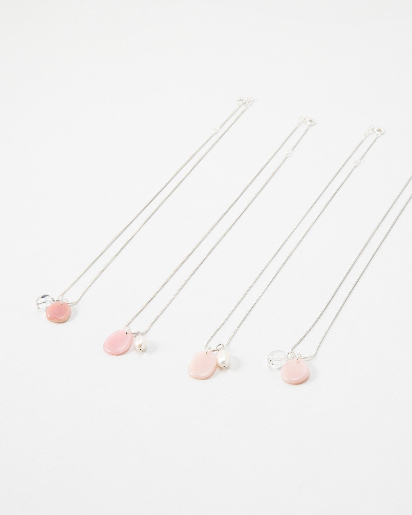 Elsita Jewelry Petal Pearl necklaces featuring delicate pink charms and small white pearls on silver chains.