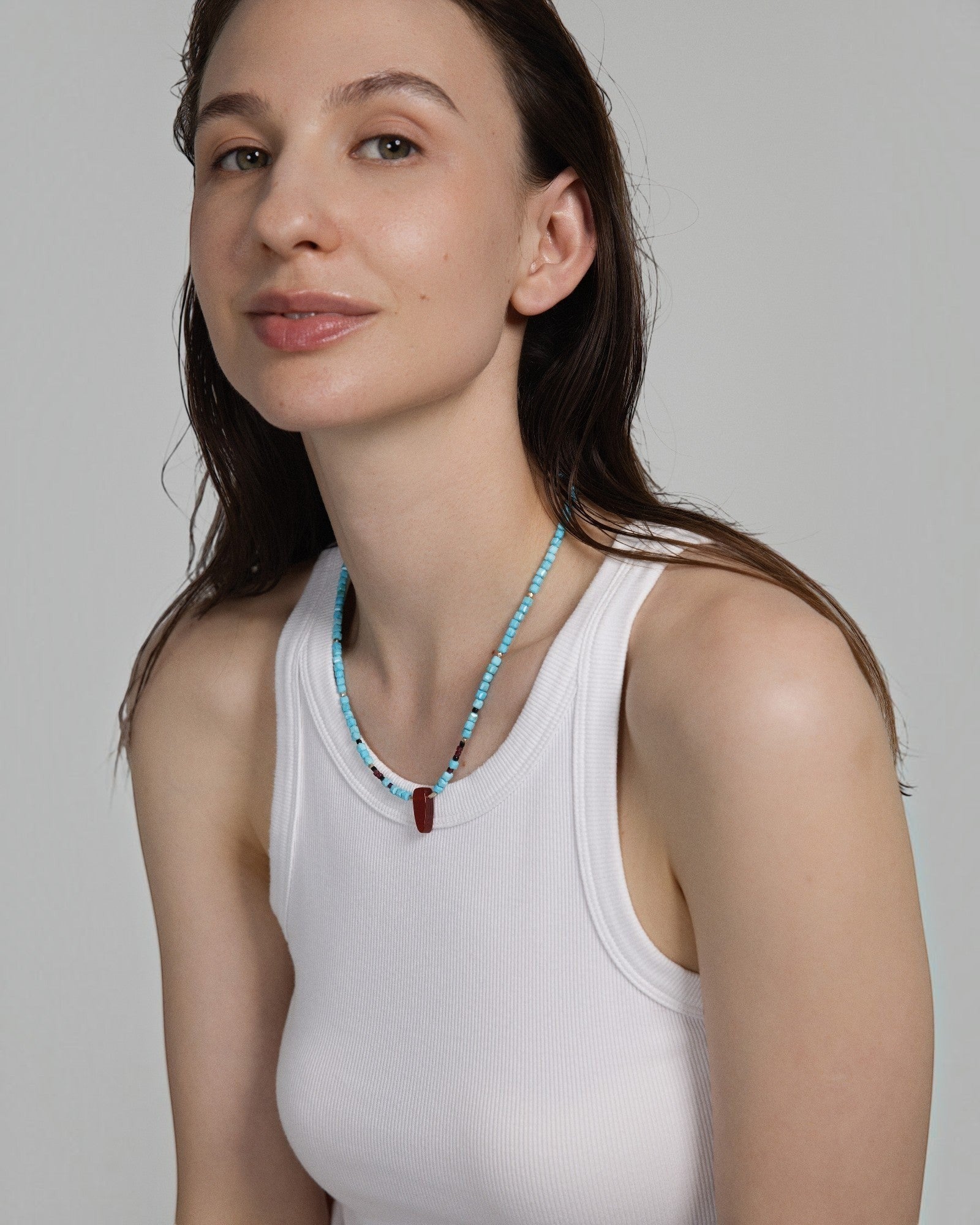 Elsita Jewelry Pixel necklace featuring turquoise cubes, red agate, and silver beads worn by a woman in a white tank top