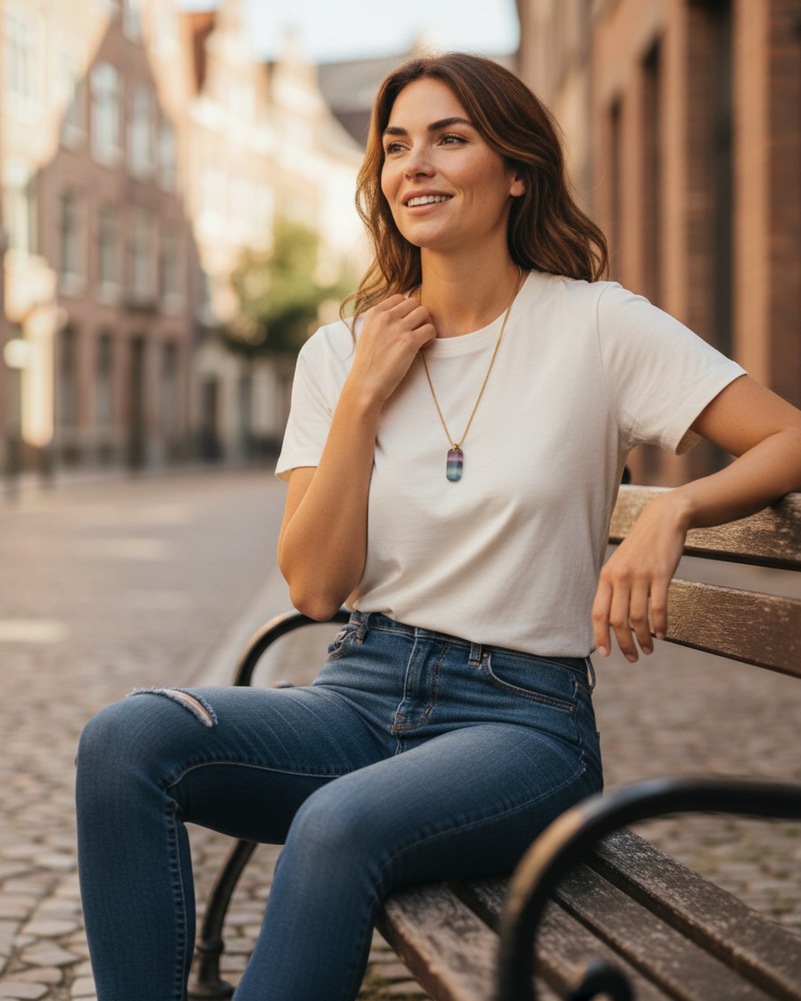 Woman wearing an Elsita Jewelry Rainbow pendant necklace with a multi-colored gemstone on a gold chain