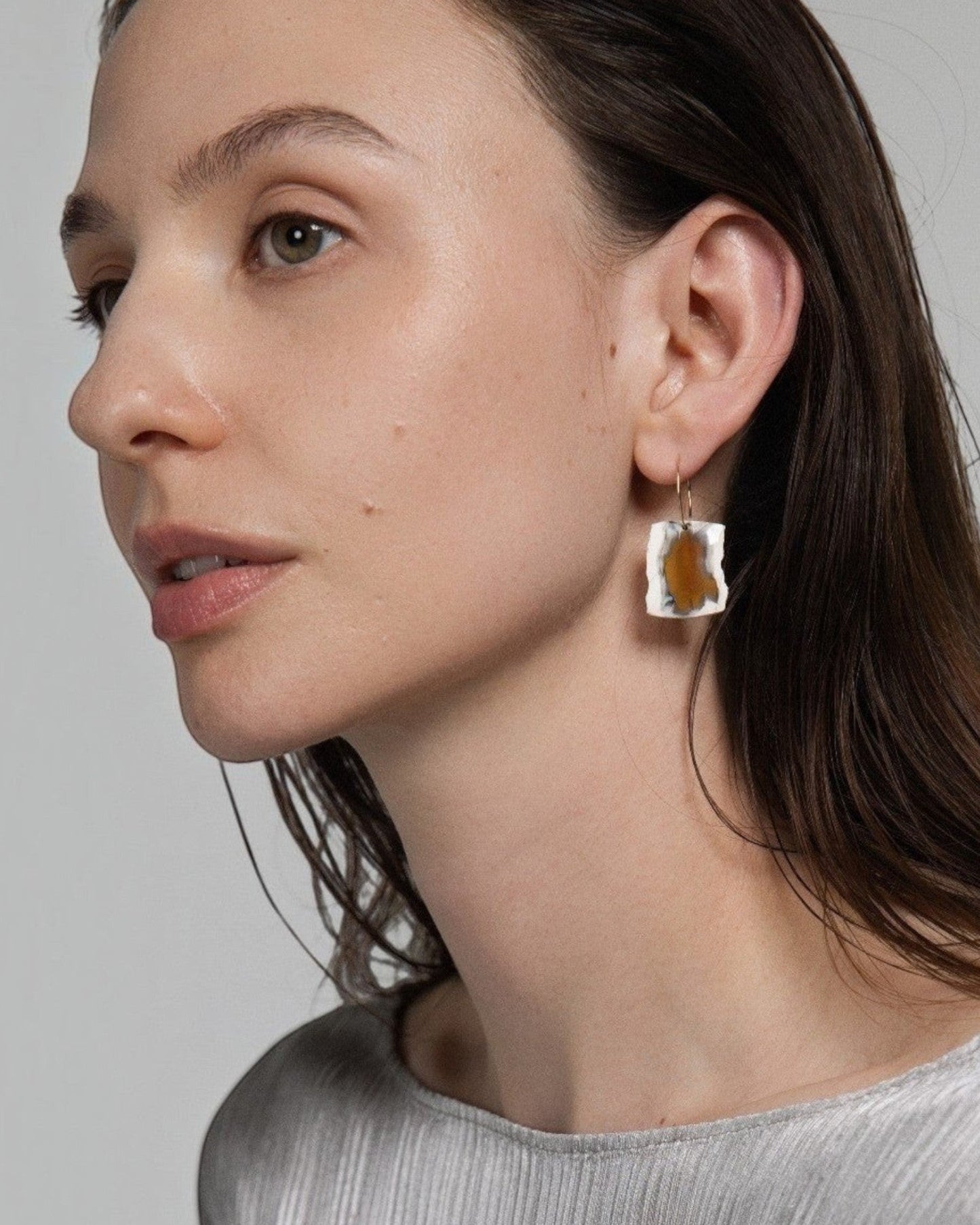 Model wearing Elsita Jewelry raw Indonesian agate earrings on 14K gold-filled hoops against a neutral background.