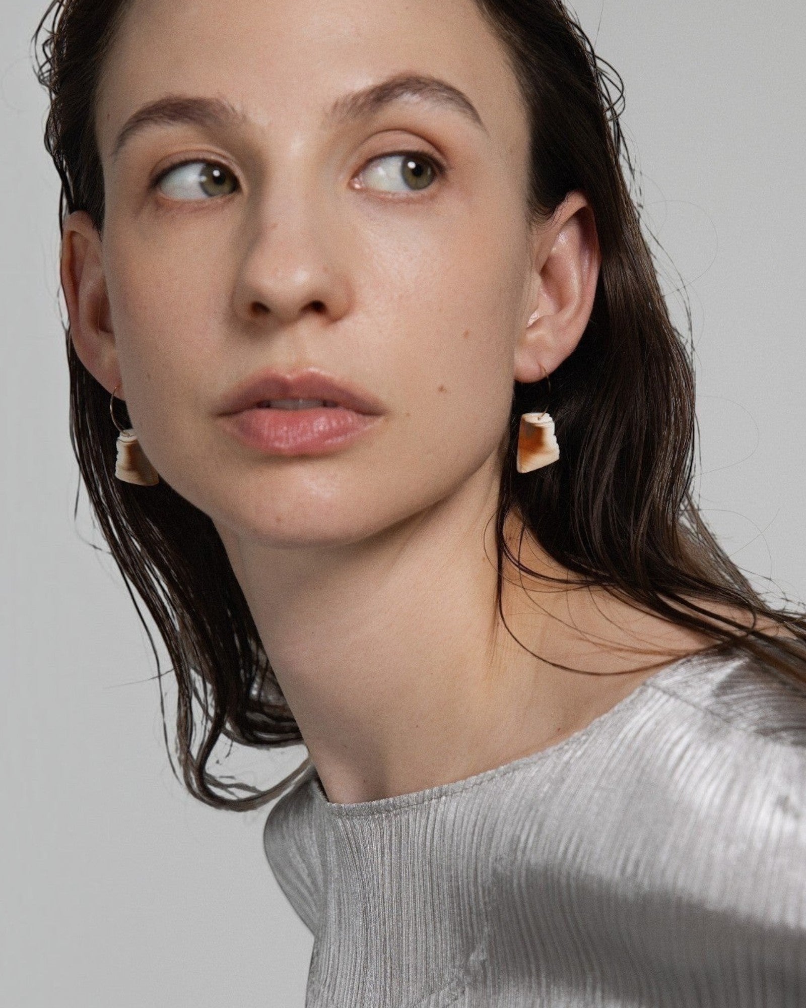 Elsita Jewelry Wild 5 raw Indonesian agate earrings on 14K gold-filled hoops worn by a woman in a silver top.