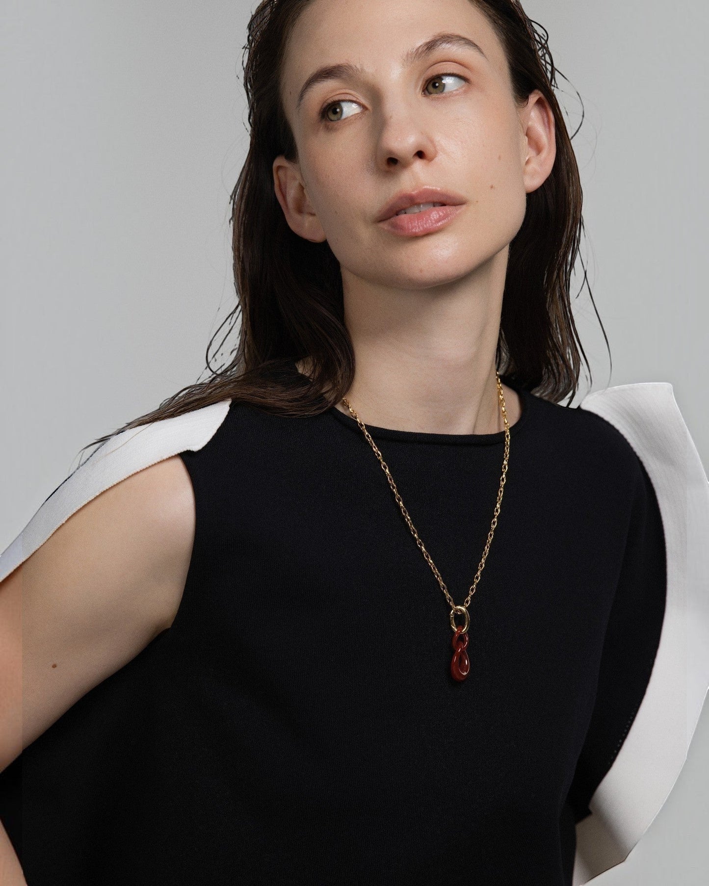Model wearing an Elsita Jewelry Link Red necklace featuring a hand-carved red agate interlocked chain pendant on gold chain