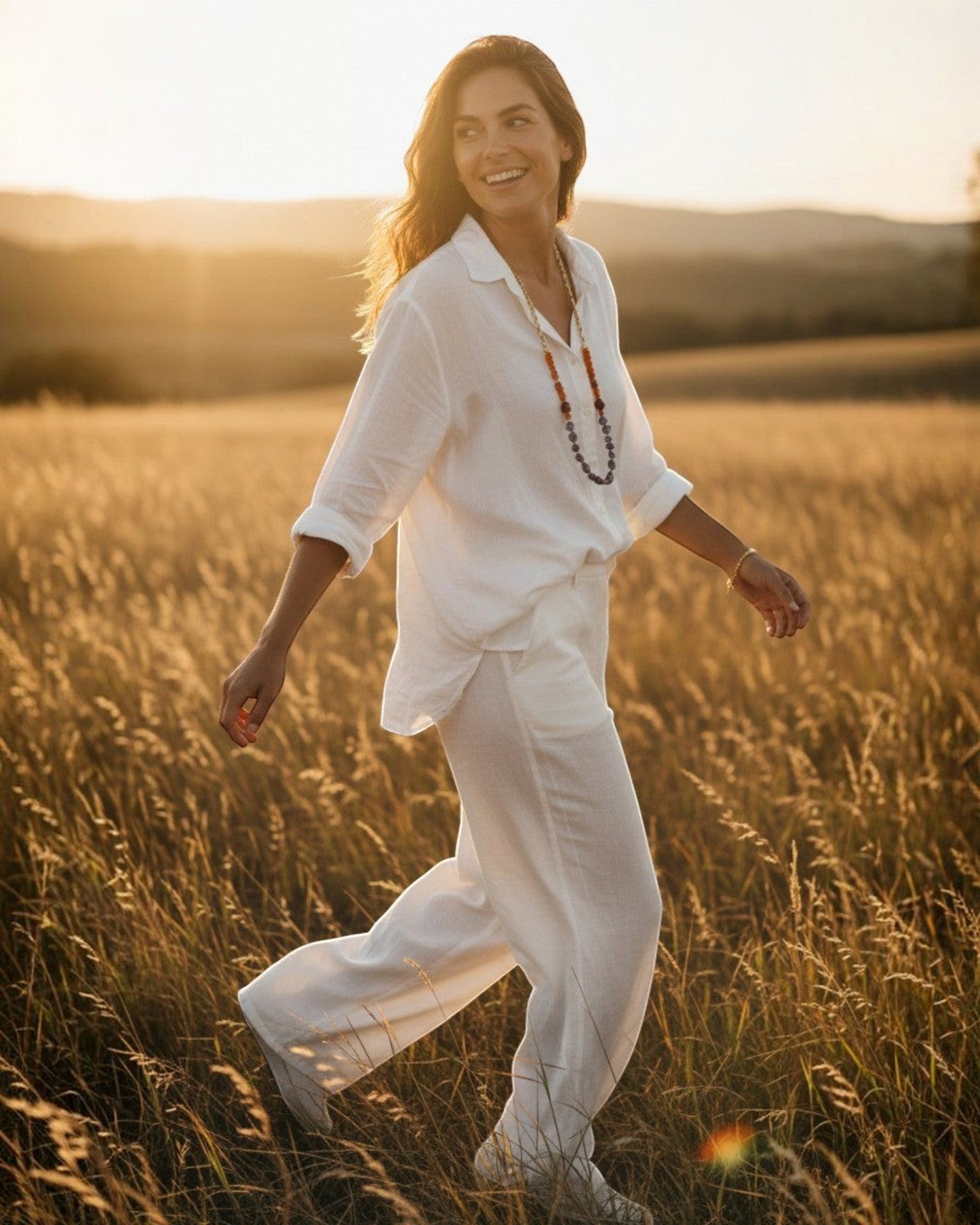 Woman wearing an Elsita Jewelry beaded necklace in a golden field at sunset