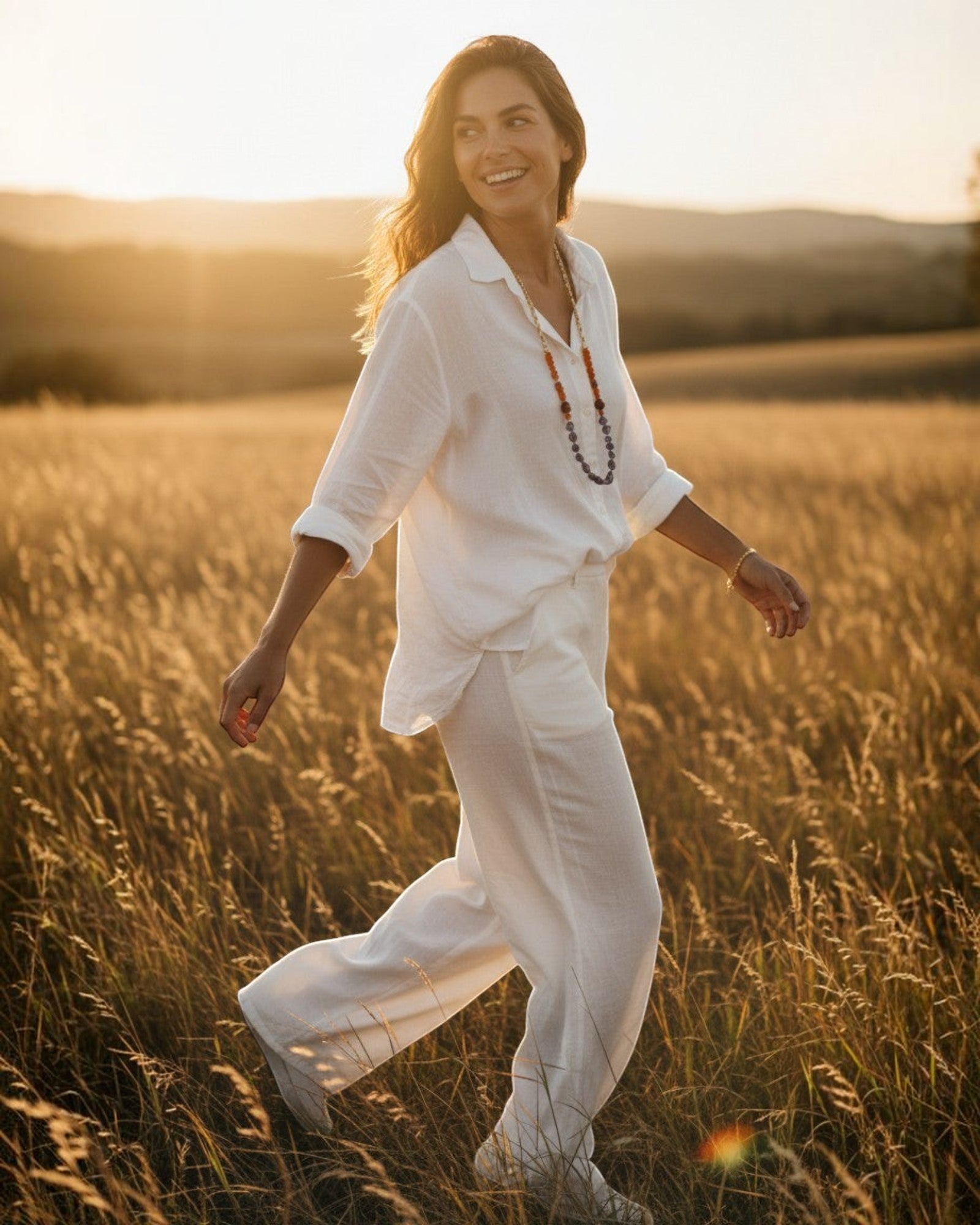 Woman wearing an Elsita Jewelry beaded necklace in a golden field at sunset