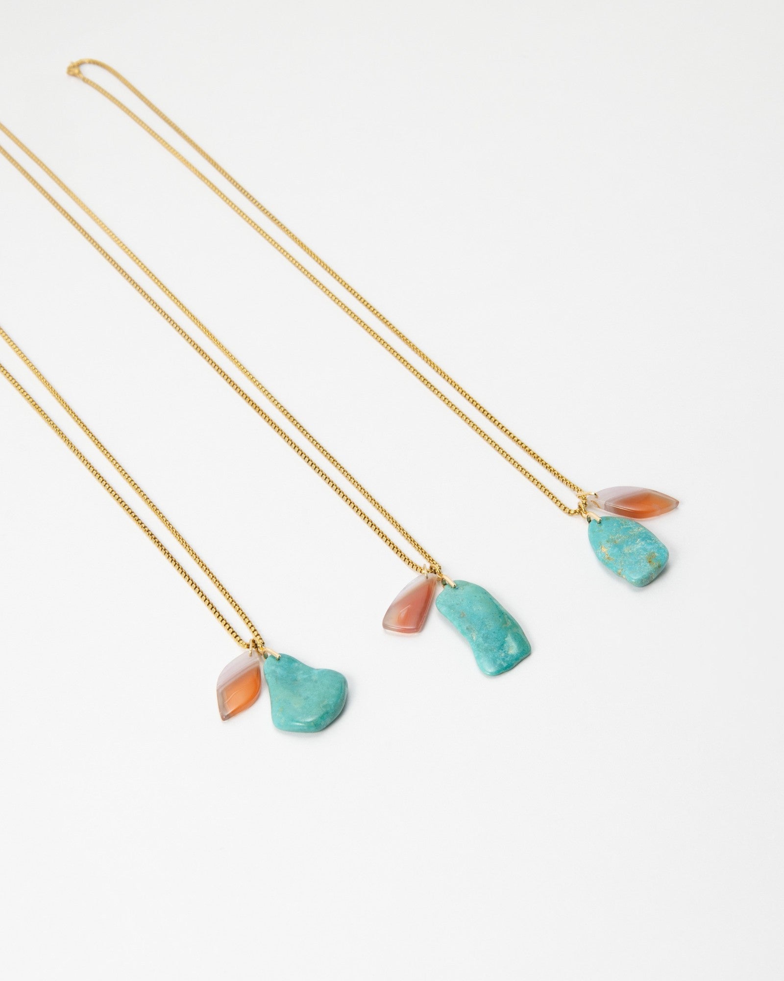 Three Elsita Jewelry Rusty I gold chain necklaces featuring raw turquoise and translucent orange stone pendants