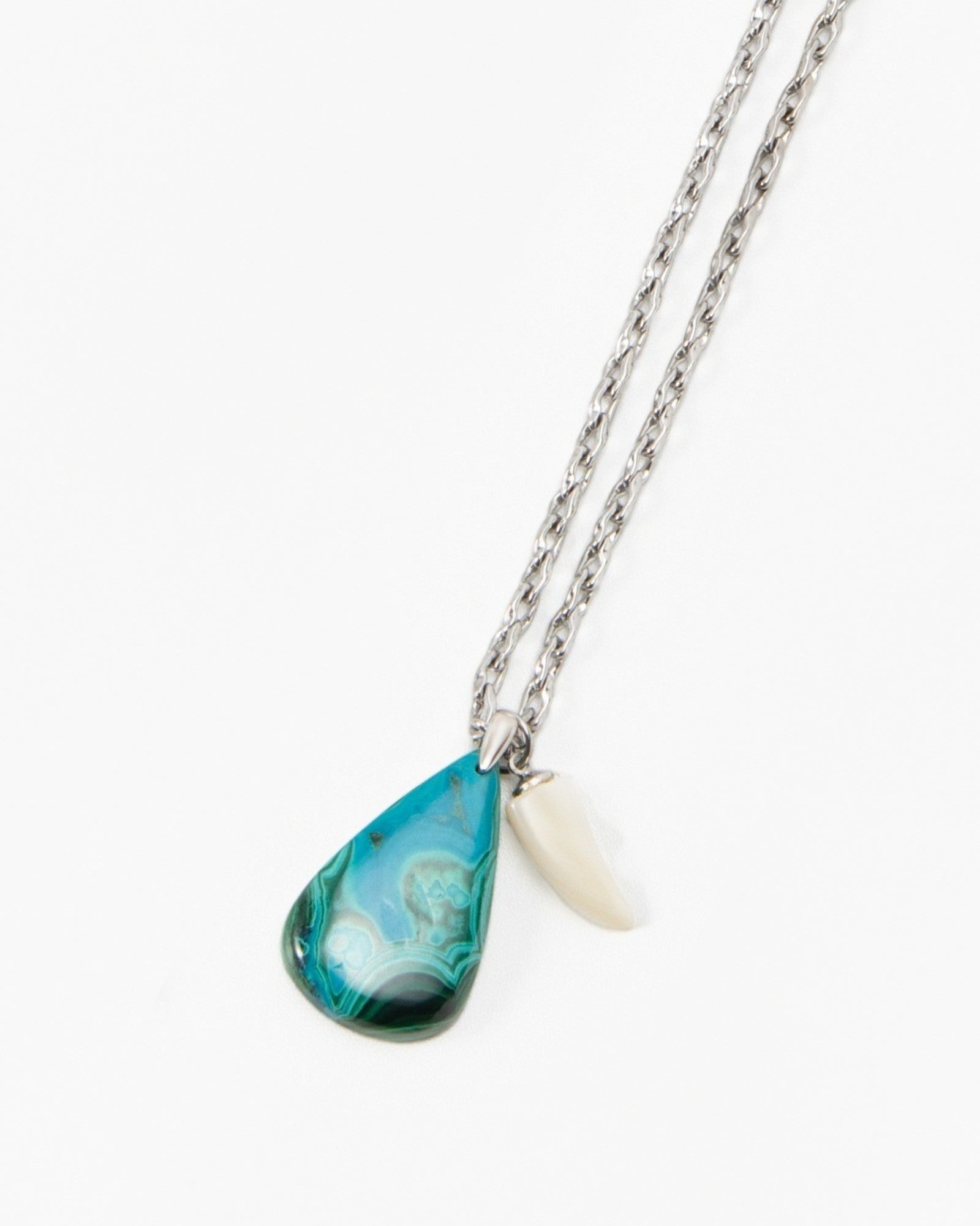 Elsita Jewelry Lagoon IV necklace featuring a teal teardrop pendant and a small white shell charm on a silver chain.
