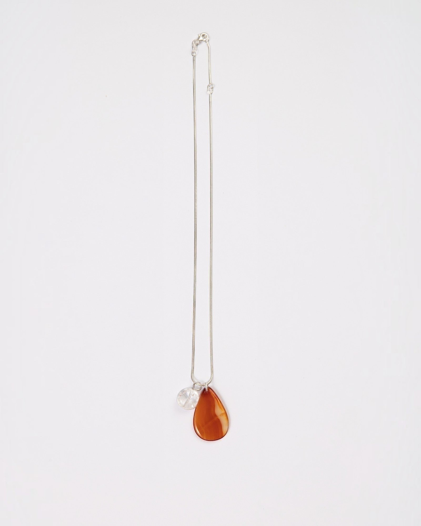 Elsita Jewelry Soda II necklace featuring a teardrop red agate and clear quartz pendant on a sterling silver chain.