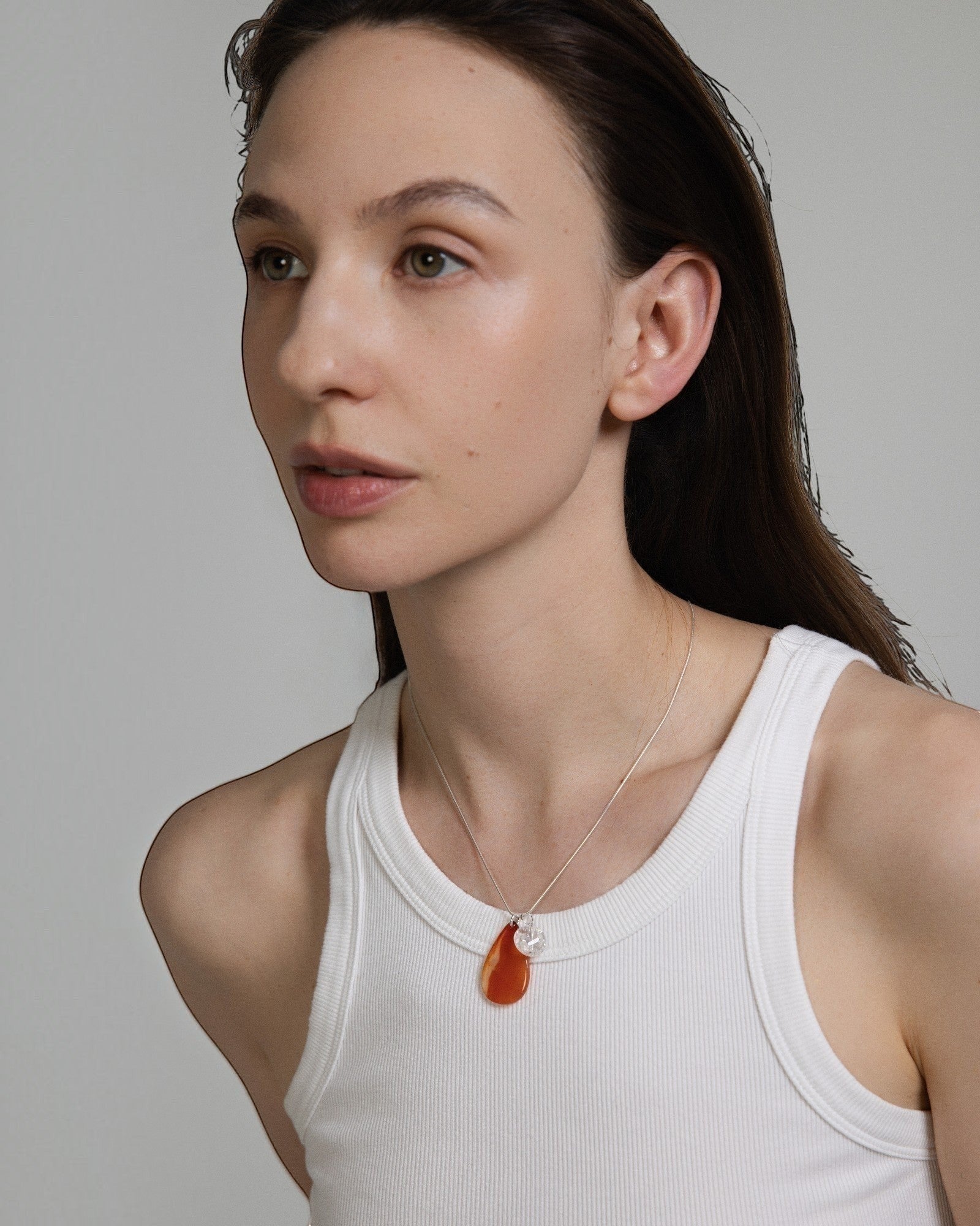 Model wearing Elsita Jewelry Soda II teardrop red agate and clear quartz pendant on a sterling silver snake chain